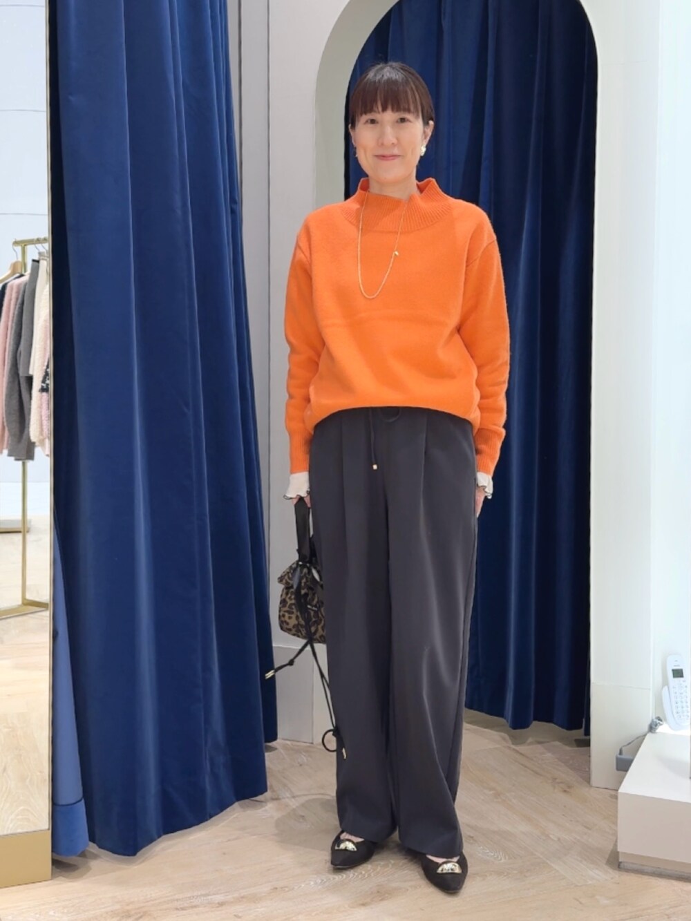 オレンジ系のニット/セーター、グレー系のその他パンツ、ホワイト系のTシャツ/カットソーを着用したレディースの冬コーディネートの9枚目の写真