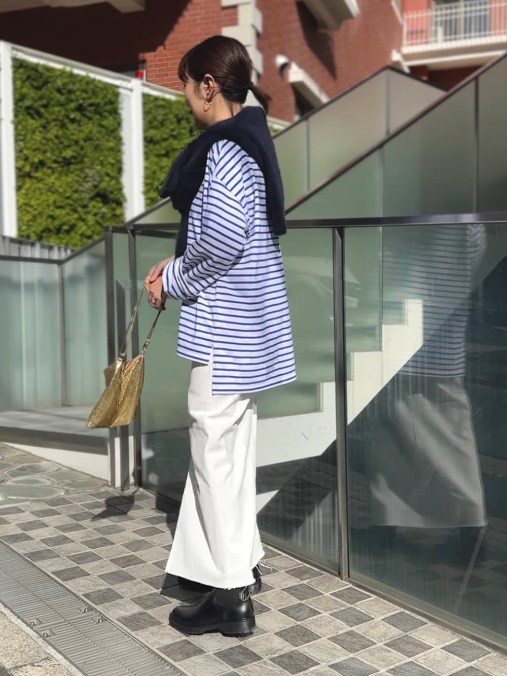 ゴールド系のクラッチバッグ、ブラック系のブーツ、ホワイト系のデニムスカートを着用したレディースの冬コーディネートの3枚目の写真