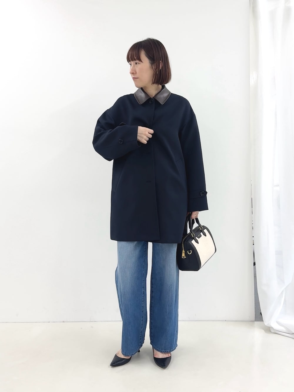 ブラック系のボストンバッグ、ホワイト系のTシャツ/カットソー、ブルー系のステンカラーコートを着用したレディースの冬コーディネートの2枚目の写真