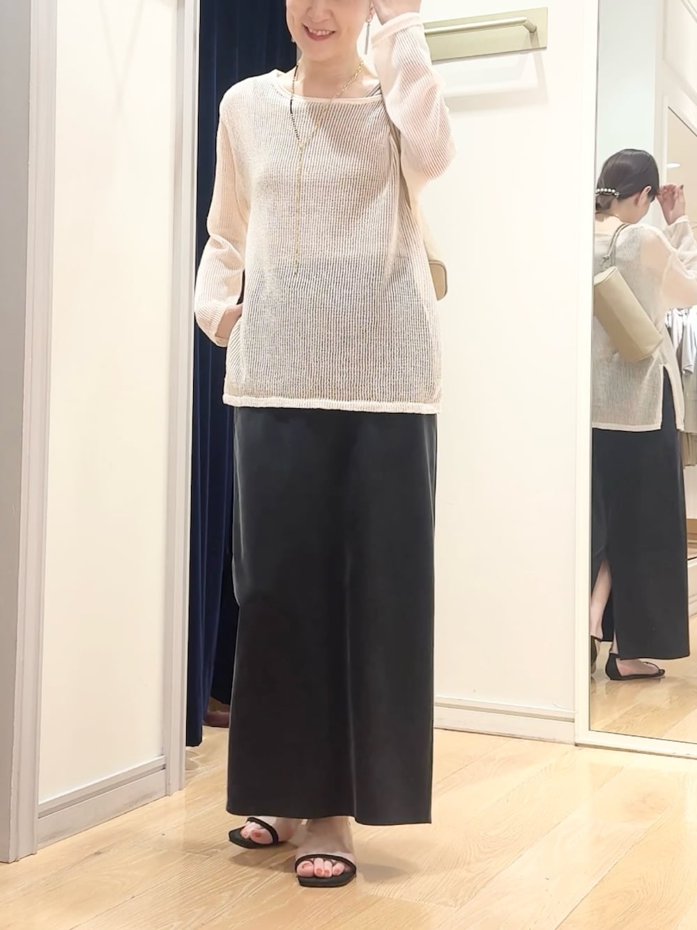 ブラック系のスカート、ベージュ系のショルダーバッグ、ホワイト系のニット/セーターを着用したレディースの夏コーディネートの5枚目の写真