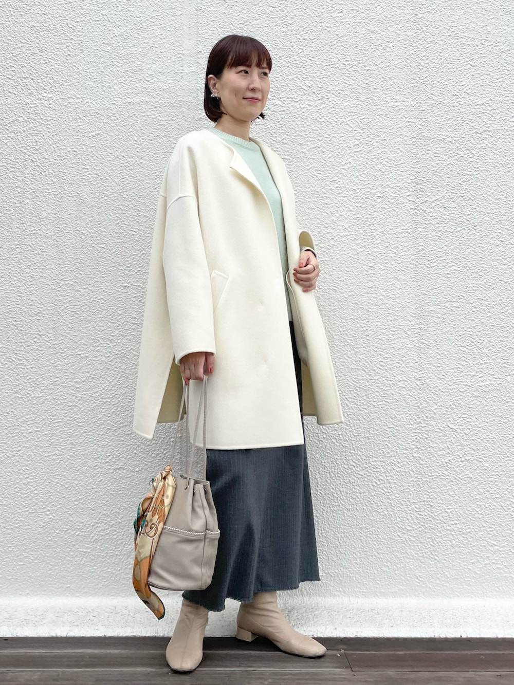 ベージュ系のトートバッグ、グレー系のスカート、グリーン系のニット/セーターを着用したレディースの冬コーディネートの5枚目の写真