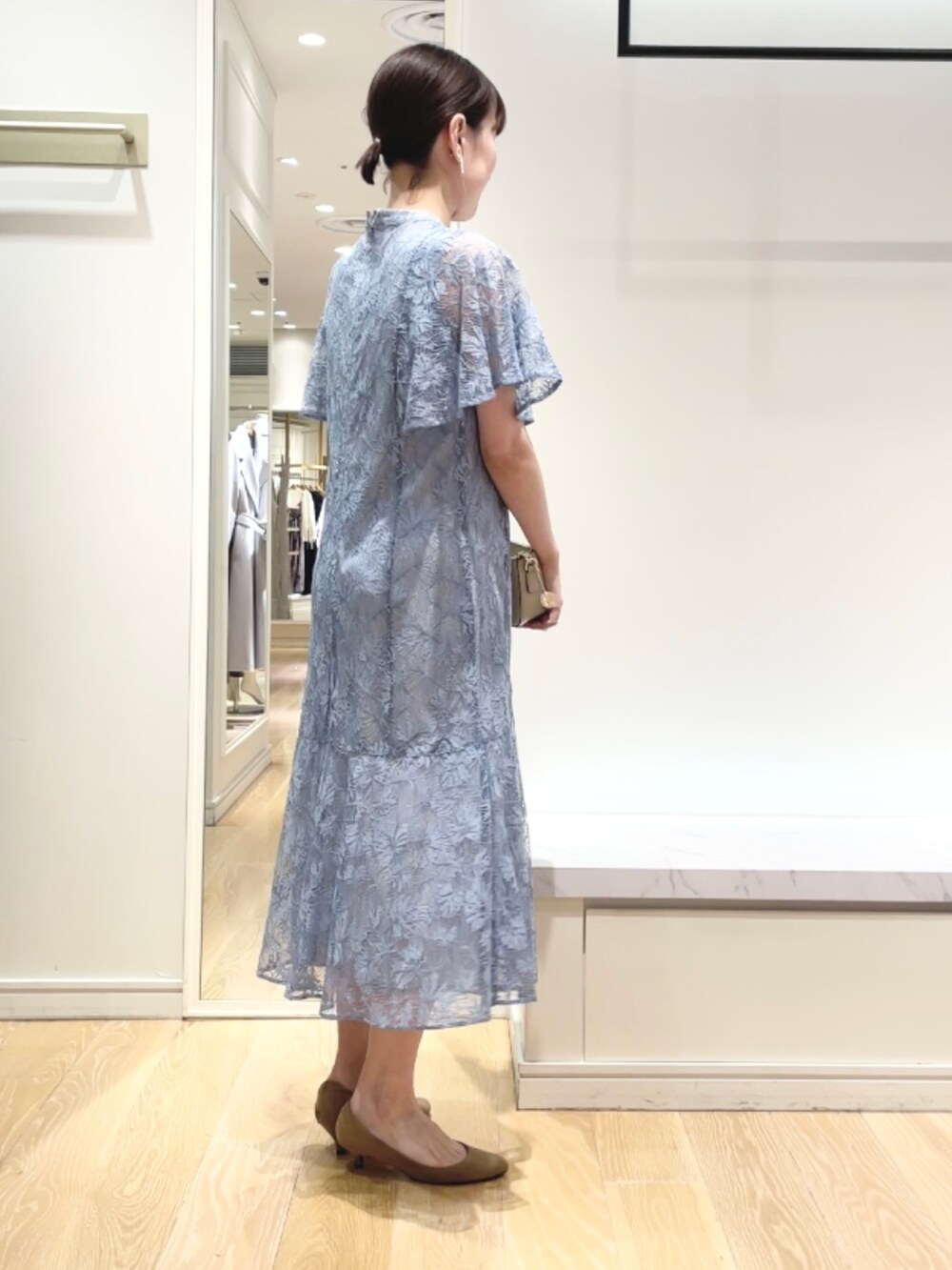 ベージュ系のショルダーバッグ、ブルー系のワンピース、ゴールド系のイヤリングを着用したレディースの秋コーディネートの5枚目の写真