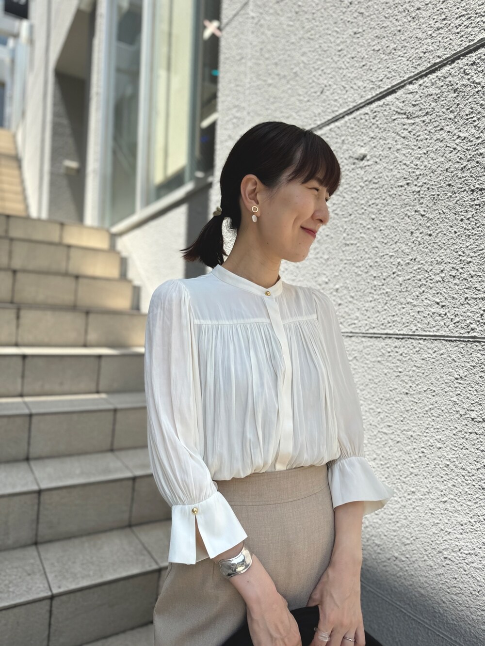 ブルー系のショルダーバッグ、ゴールド系のパンプス、ベージュ系のスカートを着用したレディースの春コーディネートの6枚目の写真