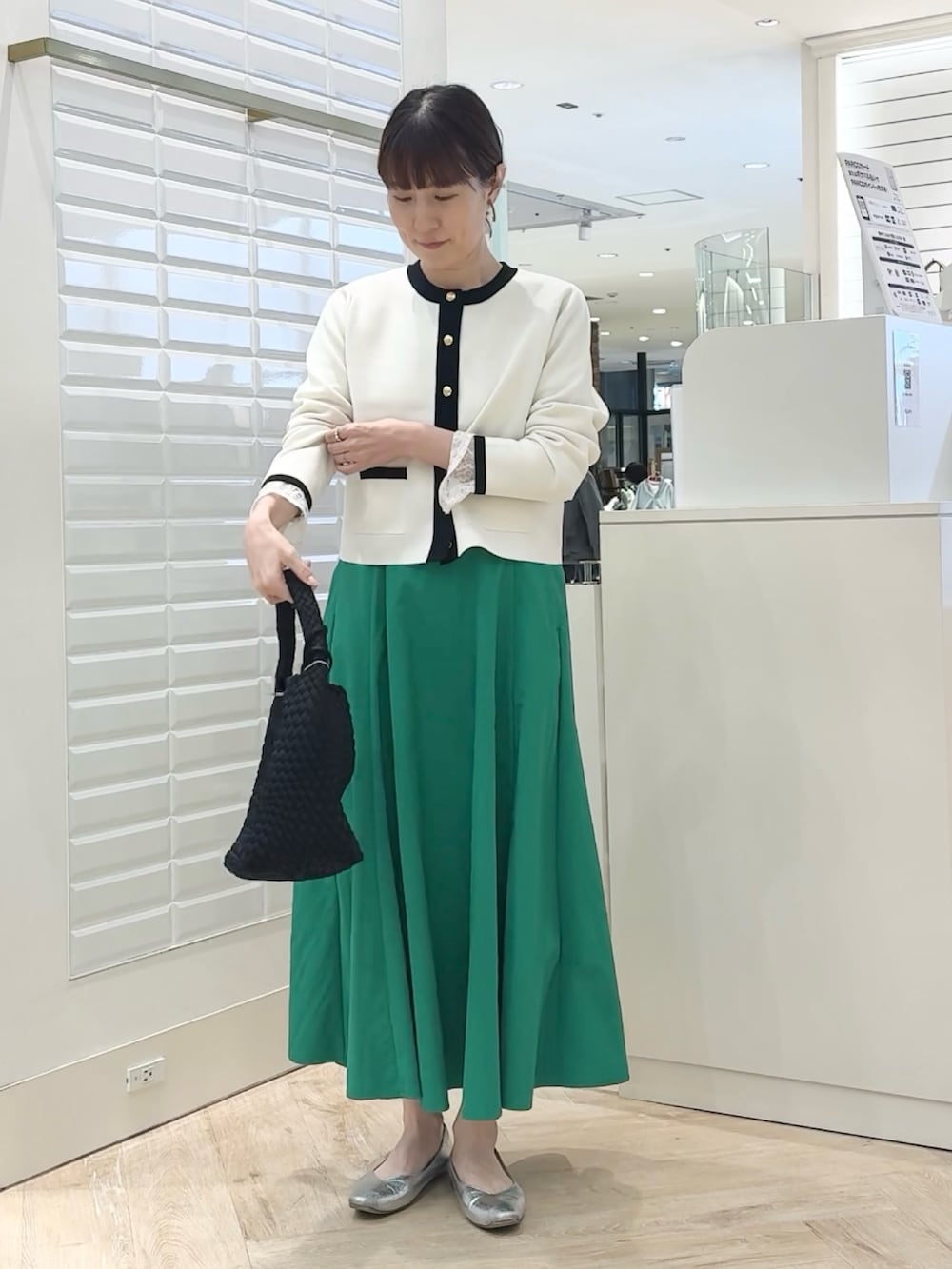 ホワイト系のカーディガン/ボレロ、グリーン系のスカート、ブラック系のショルダーバッグを着用したレディースの春コーディネートの7枚目の写真