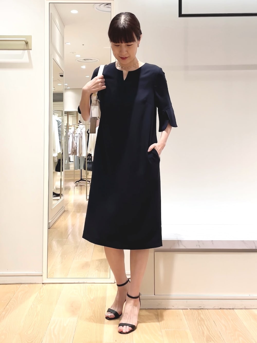 ブルー系のワンピース、ホワイト系のショルダーバッグ、シルバー系のイヤリングを着用したレディースの春コーディネートの4枚目の写真