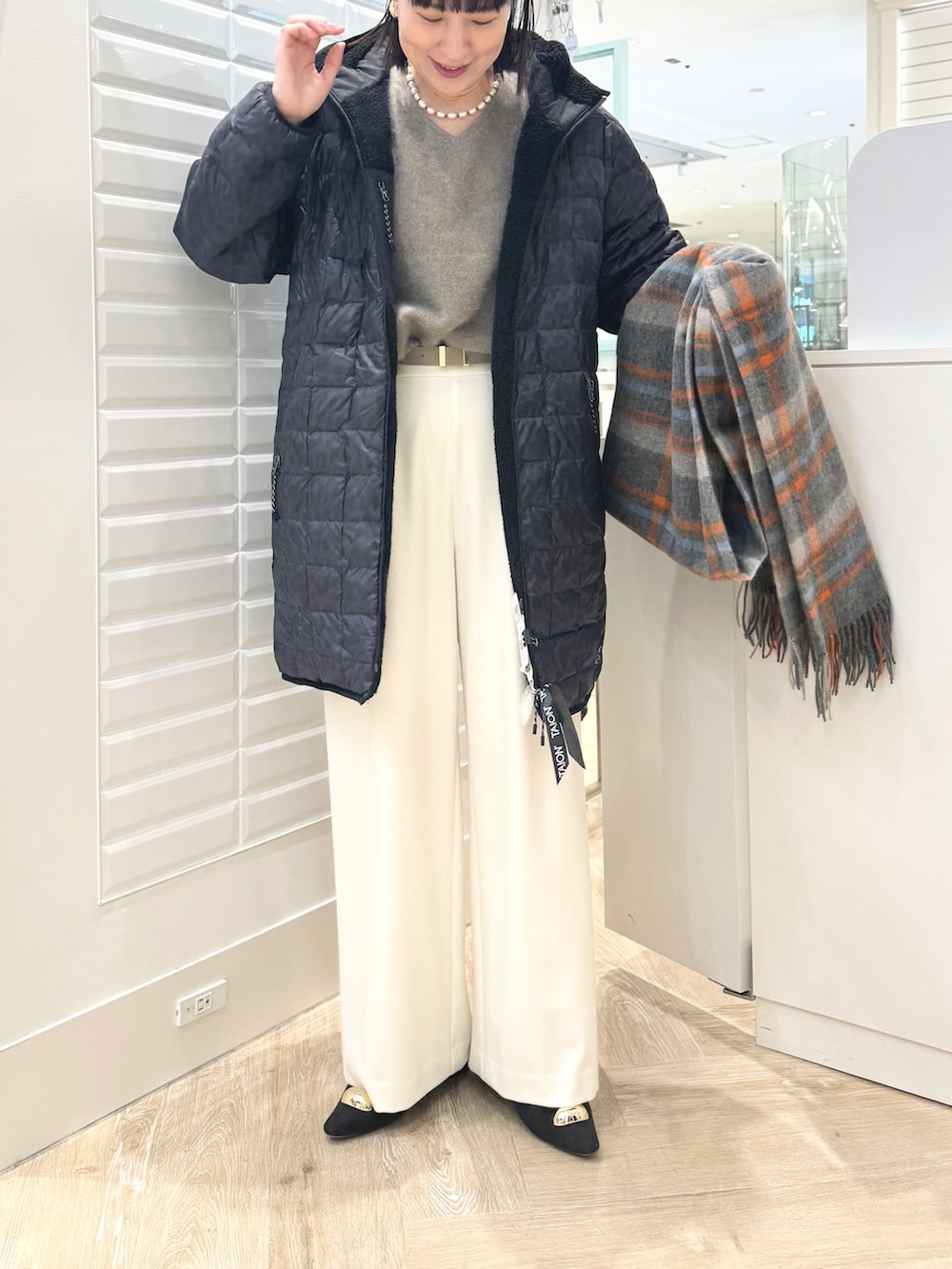 ホワイト系のその他パンツ、ベージュ系のトートバッグ、ブラック系のダウンジャケット/コートを着用したレディースの秋コーディネートの3枚目の写真