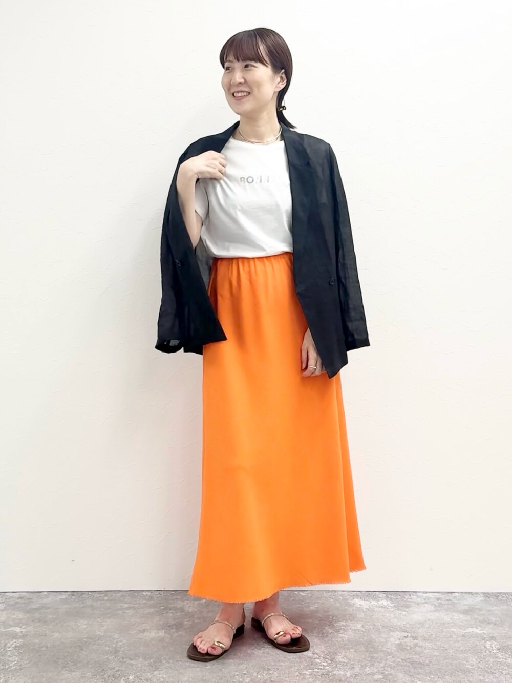 ホワイト系のTシャツ/カットソー、オレンジ系のスカート、ブラウン系のサンダルを着用したレディースの夏コーディネートの2枚目の写真