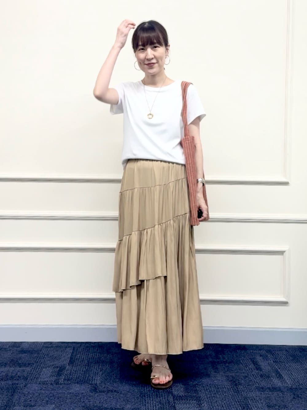 レッド系のトートバッグ、イエロー系のスカート、ホワイト系のTシャツ/カットソーを着用したレディースの夏コーディネートの9枚目の写真