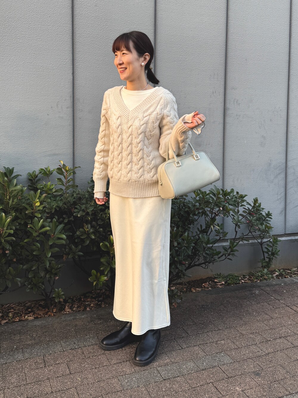 ホワイト系のニット/セーター、ホワイト系のTシャツ/カットソー、グリーン系のショルダーバッグを着用したレディースの冬コーディネートの8枚目の写真