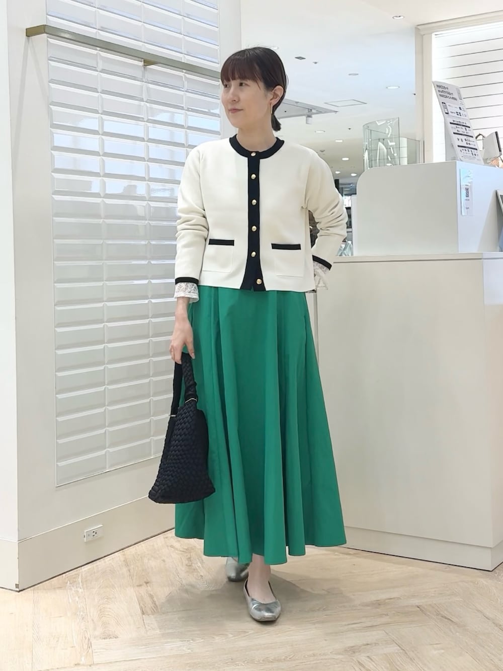 ホワイト系のカーディガン/ボレロ、グリーン系のスカート、ブラック系のショルダーバッグを着用したレディースの春コーディネートの2枚目の写真