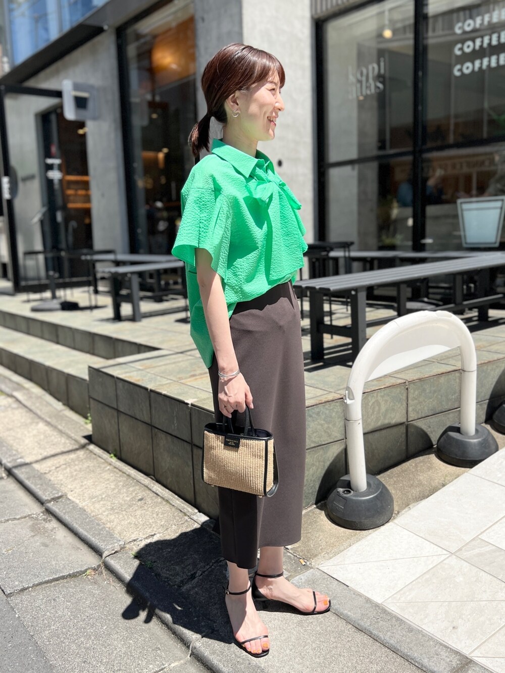 ブラック系のトートバッグ、グレー系のスカート、ブラック系のサンダルを着用したレディースの夏コーディネートの2枚目の写真