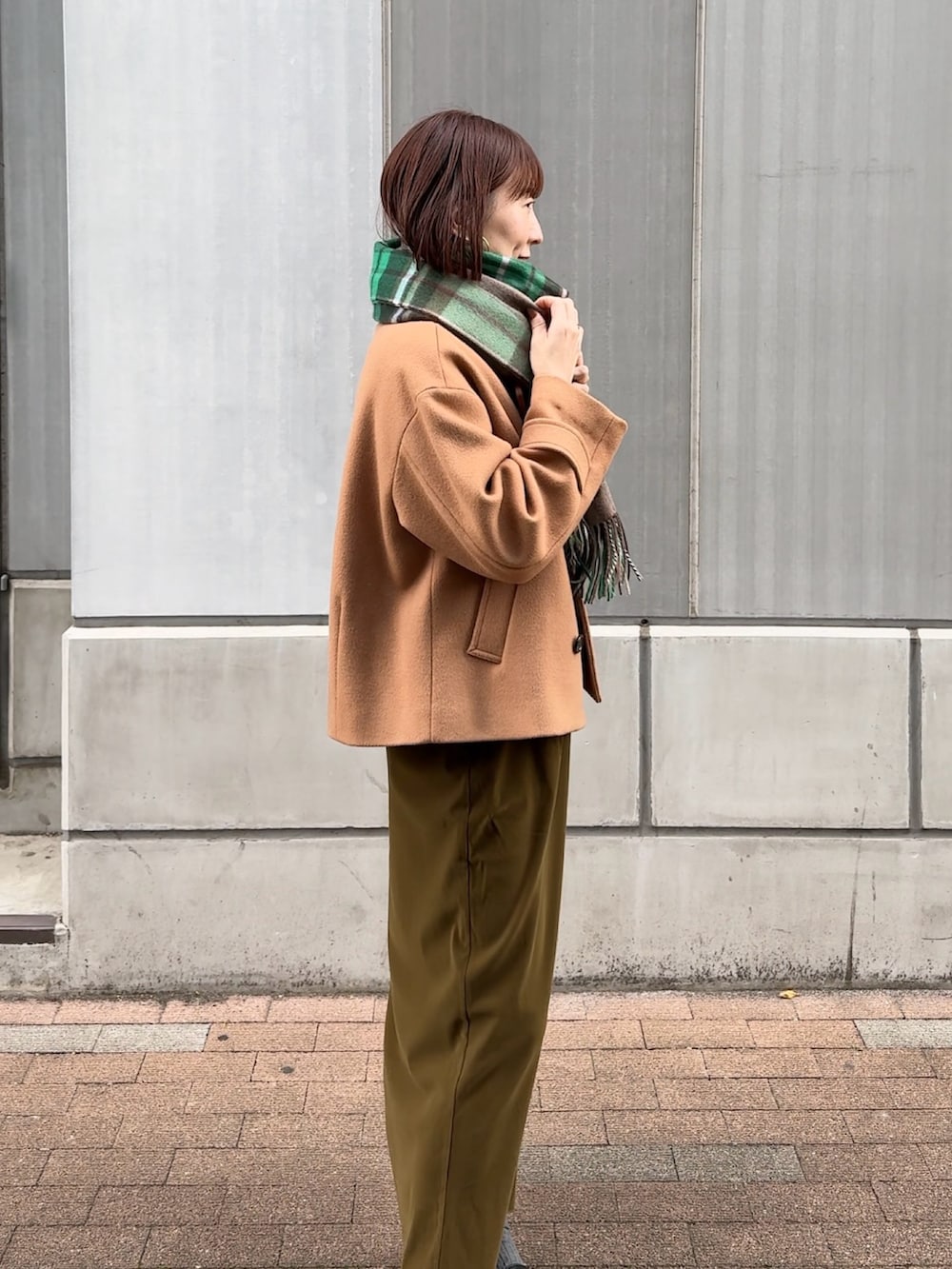 グリーン系のスカート、ホワイト系のニット/セーター、イエロー系のピーコートを着用したレディースの秋コーディネートの7枚目の写真