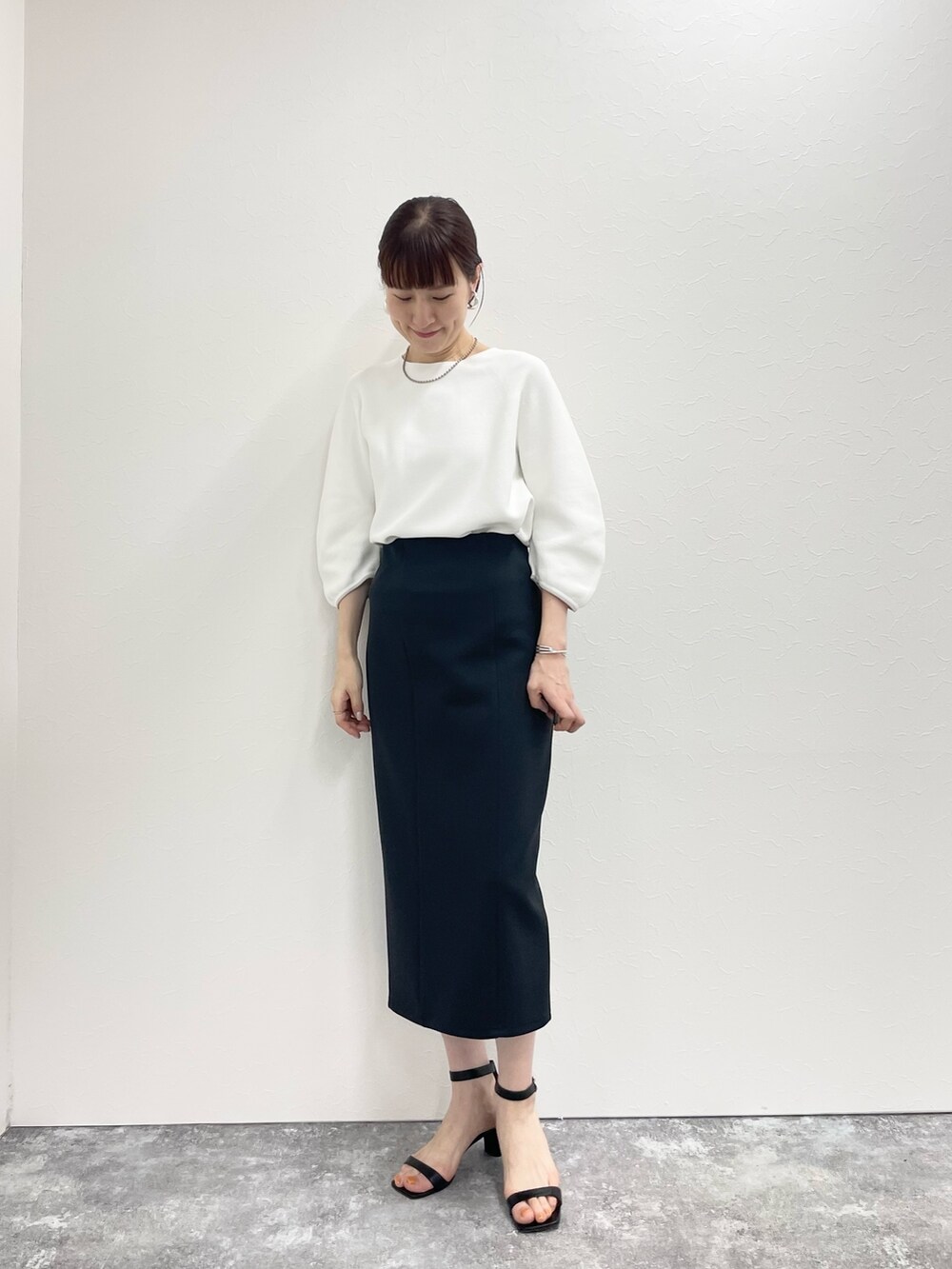 ブラック系のスカート、ホワイト系のニット/セーターを着用したレディースの春コーディネートの5枚目の写真