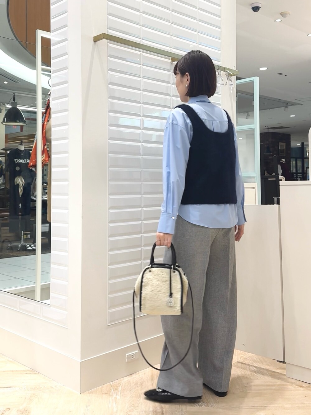 ホワイト系のボストンバッグ、ブルー系のベスト、ブルー系のシャツ/ブラウスを着用したレディースの秋コーディネートの6枚目の写真