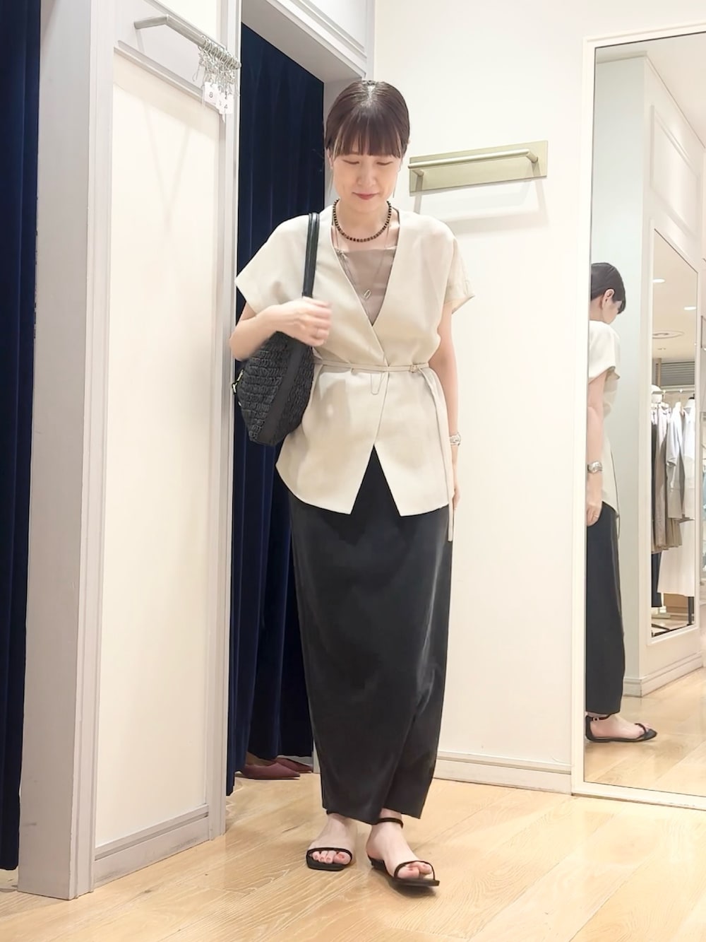 ブラック系のスカート、ブラック系のショルダーバッグ、ベージュ系のタンクトップを着用したレディースの夏コーディネートの7枚目の写真