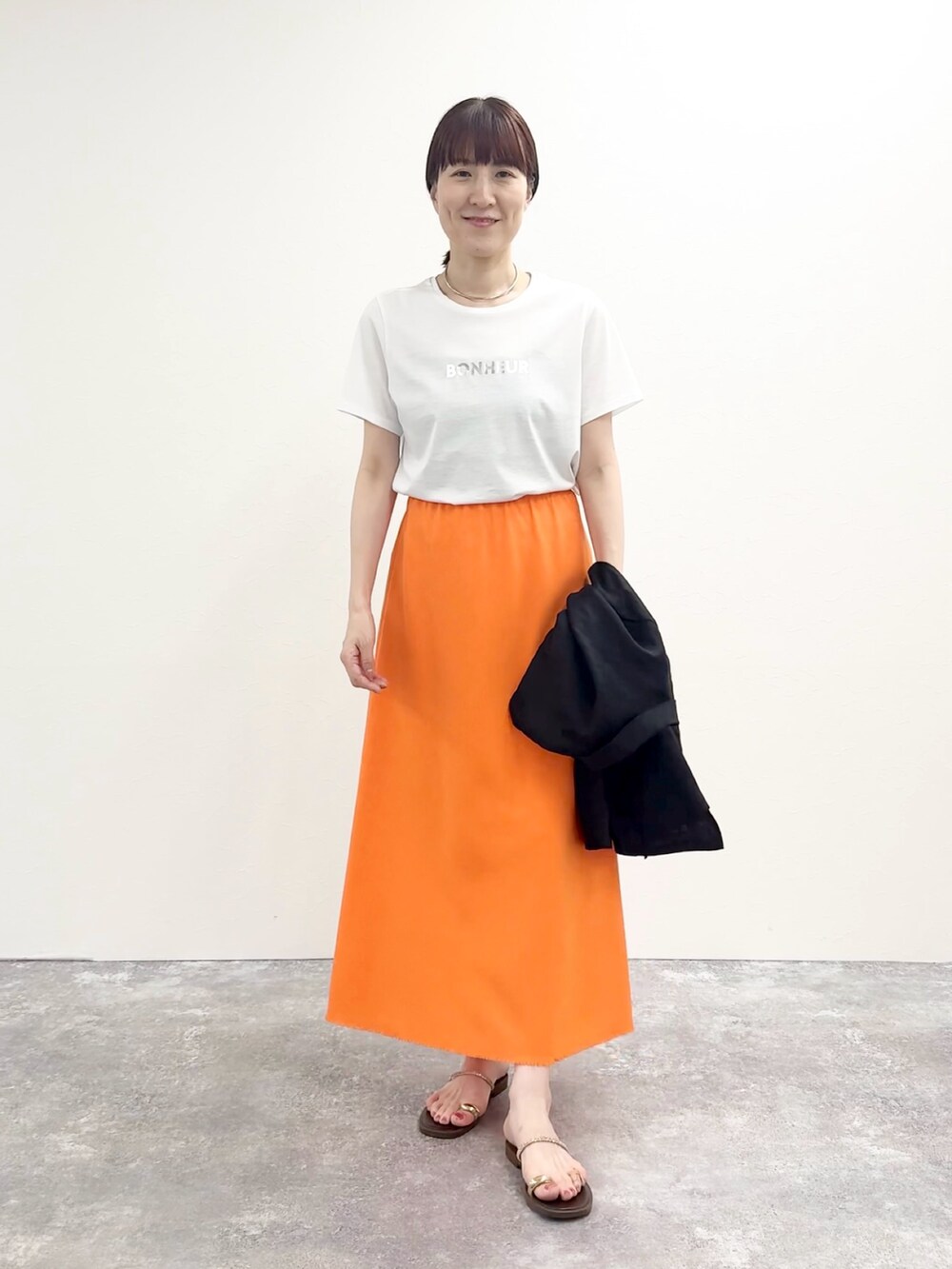 ホワイト系のTシャツ/カットソー、オレンジ系のスカート、ブラウン系のサンダルを着用したレディースの夏コーディネートの3枚目の写真
