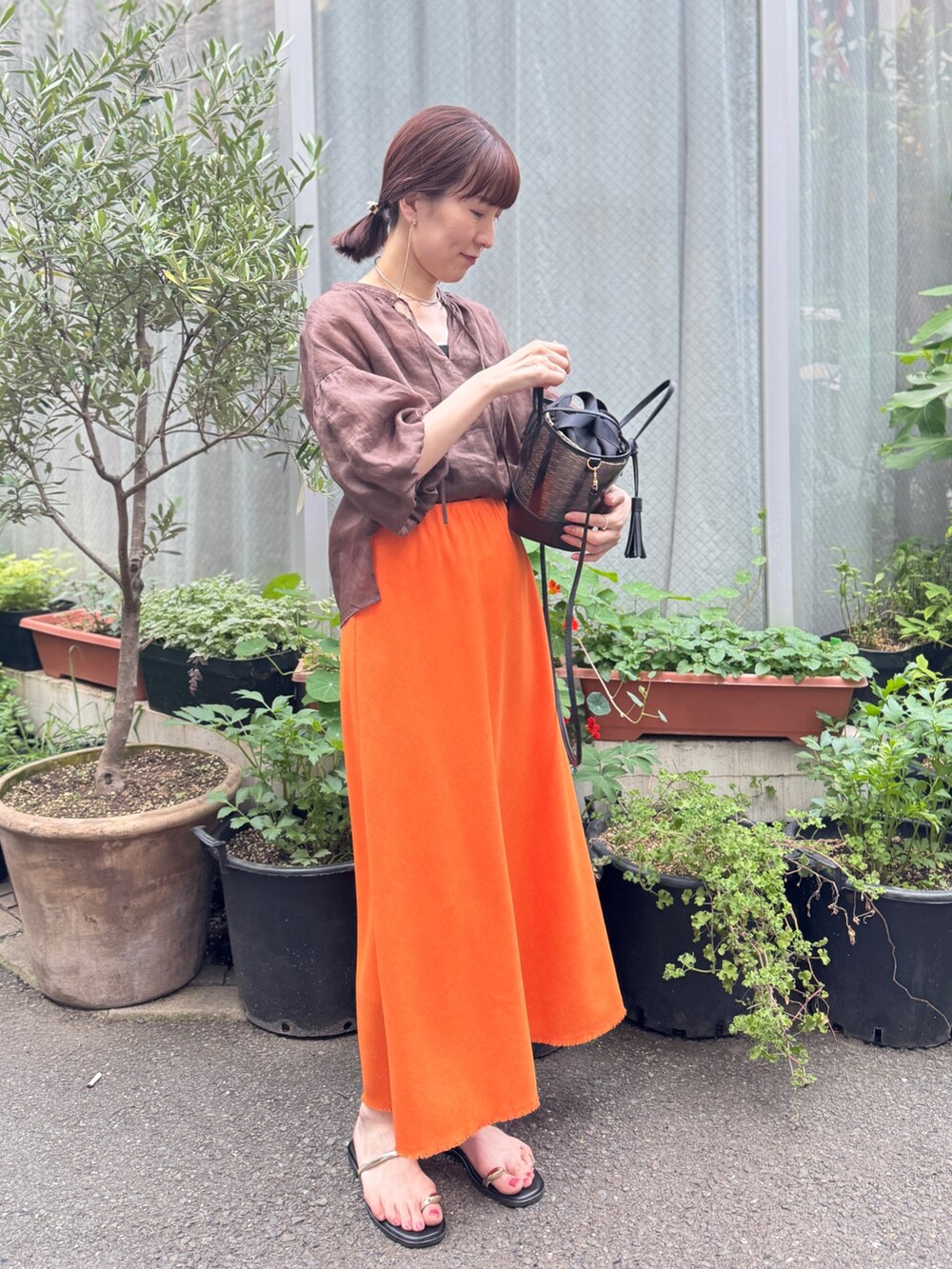 ブラック系のかごバッグ、オレンジ系のスカート、ブラウン系のシャツ/ブラウスを着用したレディースの夏コーディネートの9枚目の写真