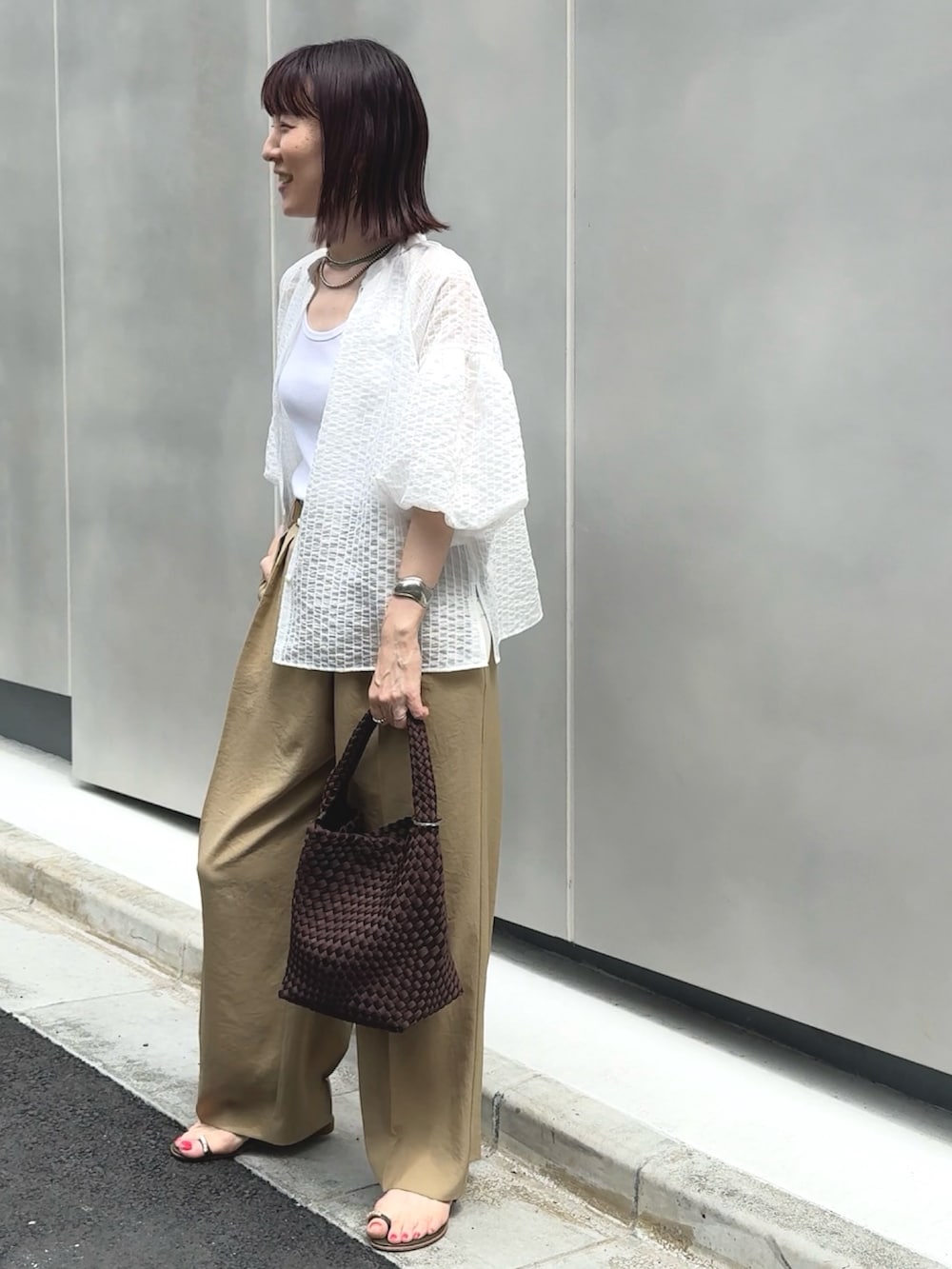 イエロー系のその他パンツ、ホワイト系のタンクトップ、ブラウン系のショルダーバッグを着用したレディースの夏コーディネートの2枚目の写真