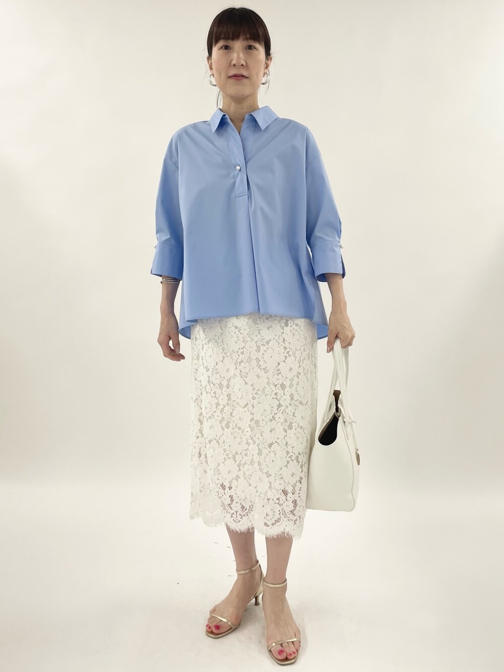 ゴールド系のサンダル、ホワイト系のスカート、ホワイト系のトートバッグを着用したレディースの春コーディネートの2枚目の写真