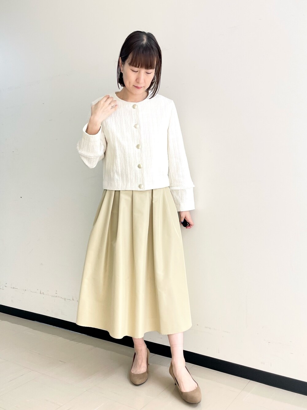 ベージュ系のスカート、ホワイト系のノーカラージャケット、ホワイト系のニット/セーターを着用したレディースの春コーディネートの6枚目の写真