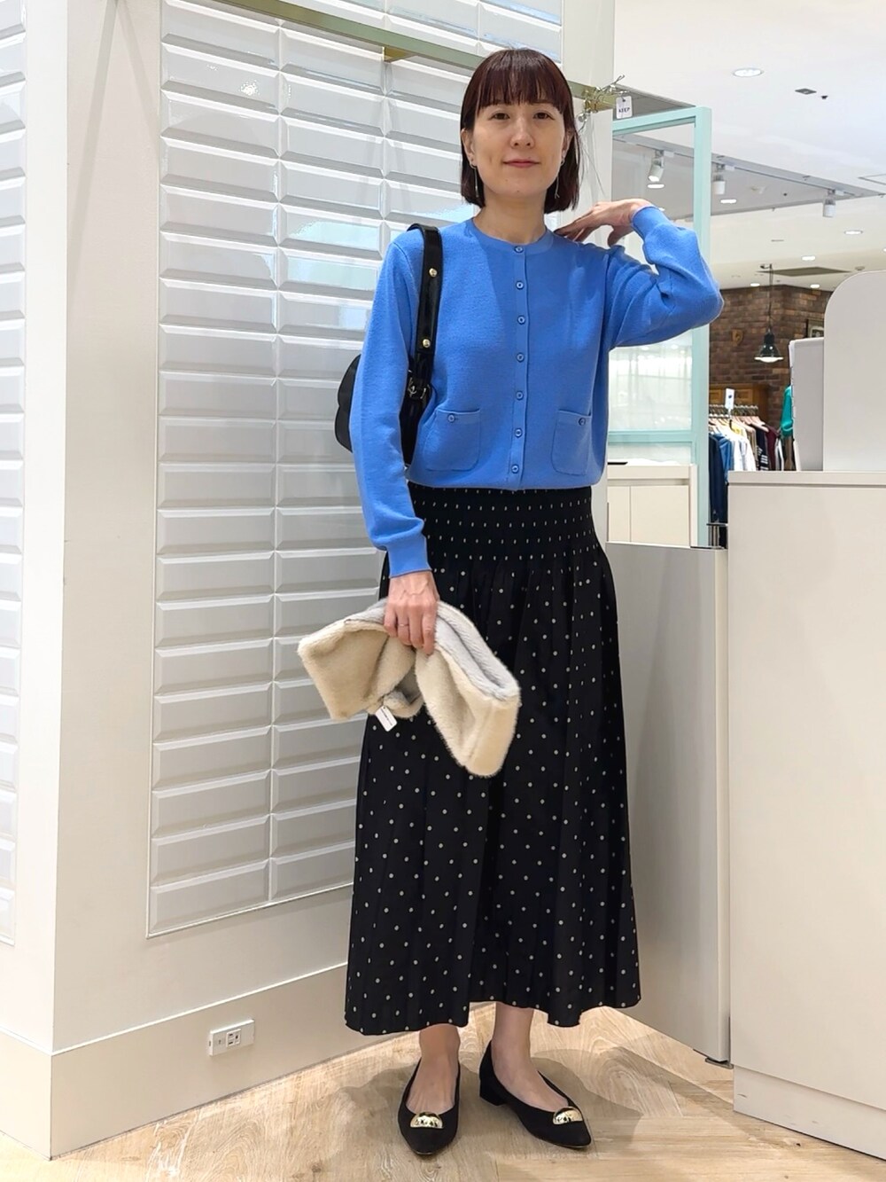 ブラック系のショルダーバッグ、ブルー系のカーディガン/ボレロ、ブラック系のスカートを着用したレディースの秋コーディネートの7枚目の写真