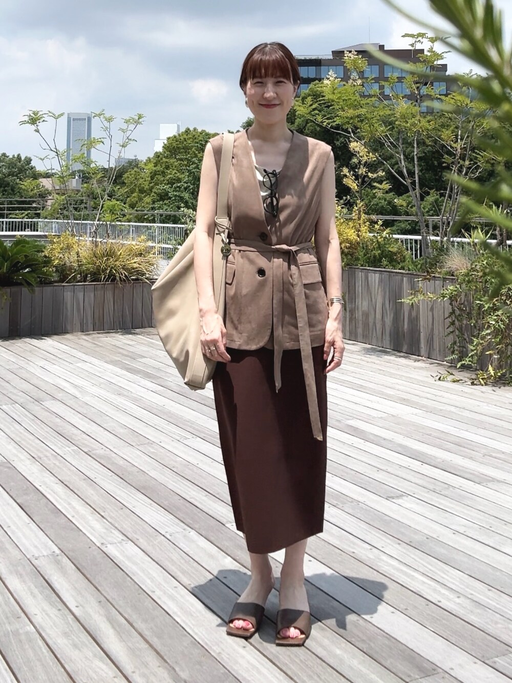 ゴールド系のタンクトップ、ベージュ系のベスト、ベージュ系のショルダーバッグを着用したレディースの秋コーディネートの2枚目の写真