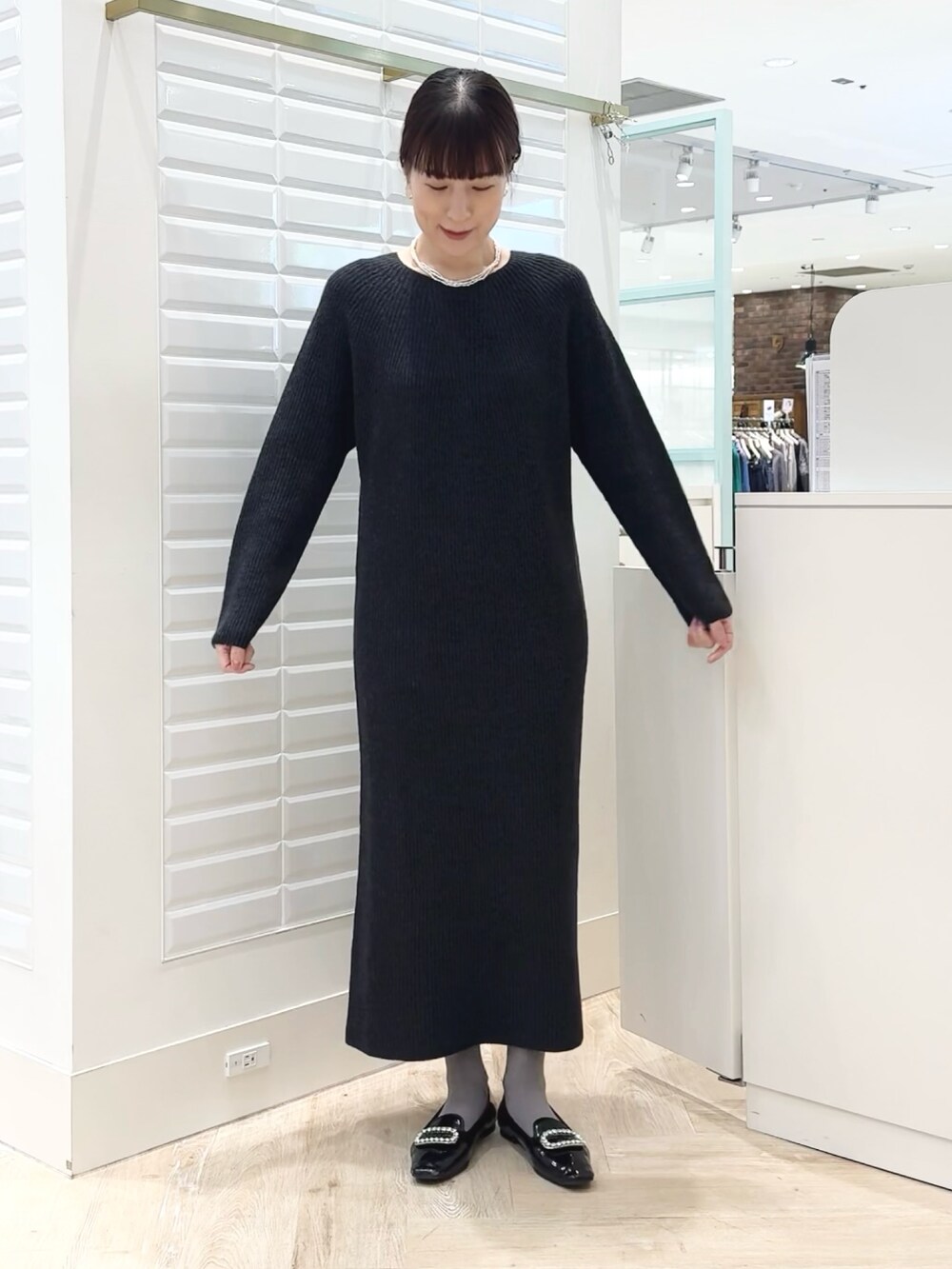 グレー系のワンピース、ゴールド系のイヤリング、ホワイト系のネックレスを着用したレディースの冬コーディネートの5枚目の写真