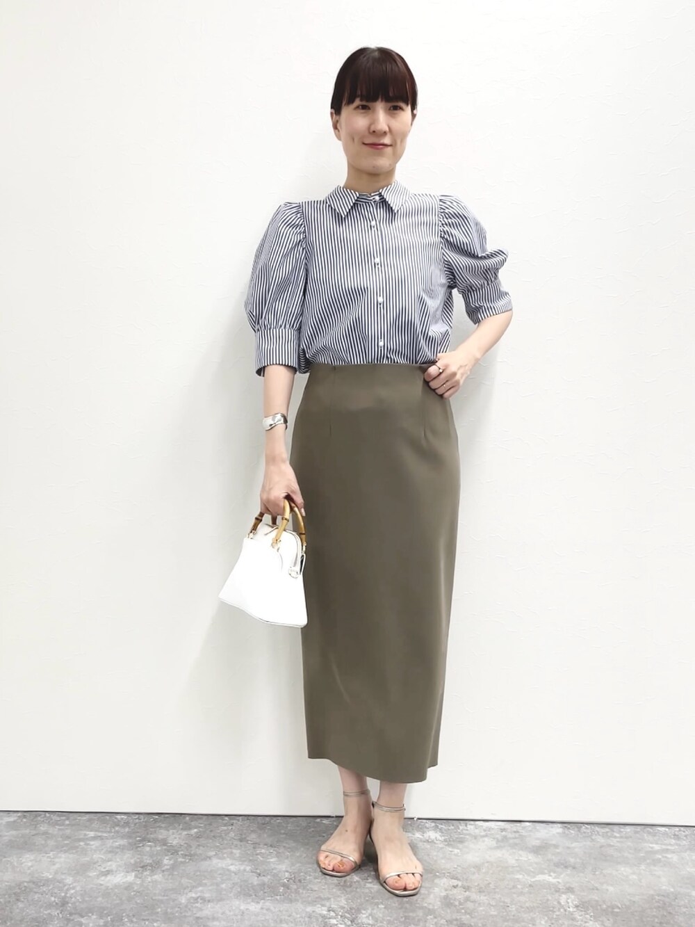シルバー系のサンダル、グリーン系のスカート、ホワイト系のショルダーバッグを着用したレディースの春コーディネートの3枚目の写真