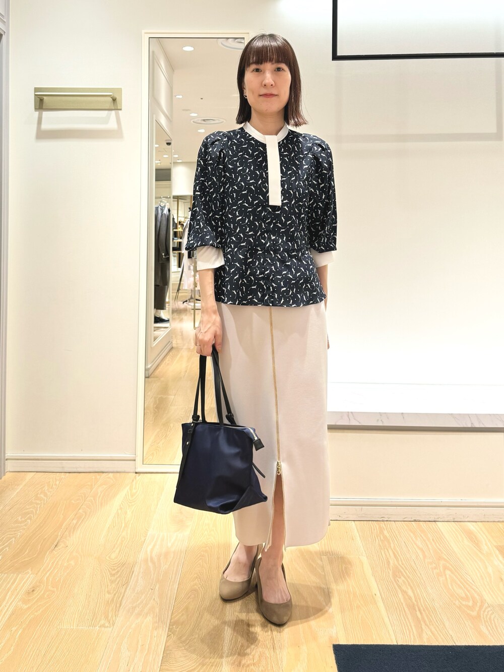 ベージュ系のスカート、ブルー系のトートバッグ、ブルー系のシャツ/ブラウスを着用したレディースの秋コーディネートの8枚目の写真