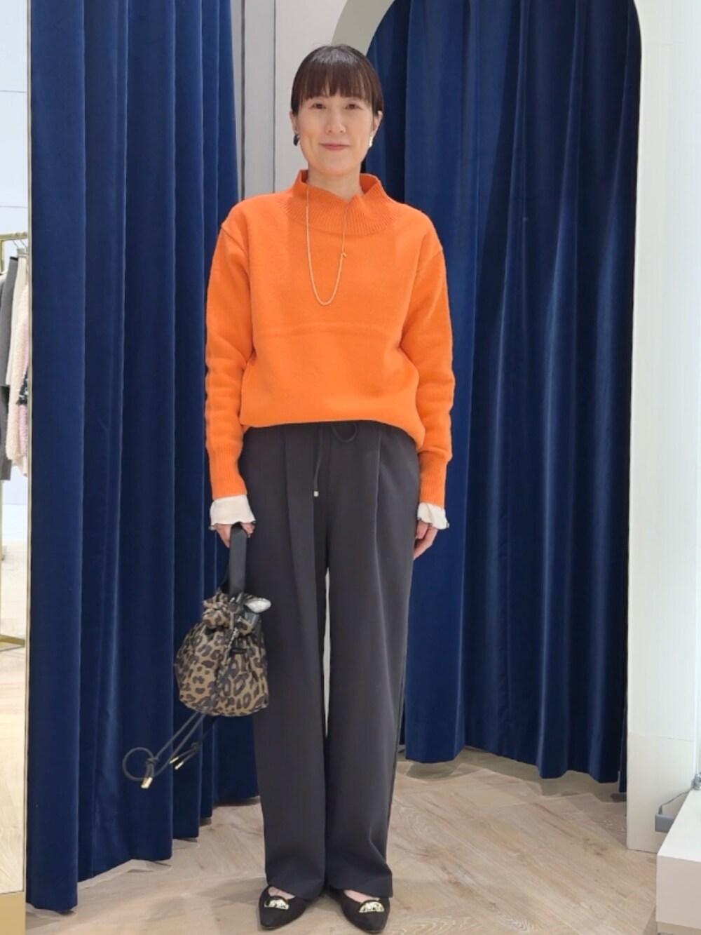 オレンジ系のニット/セーター、グレー系のその他パンツ、ホワイト系のTシャツ/カットソーを着用したレディースの冬コーディネートの5枚目の写真