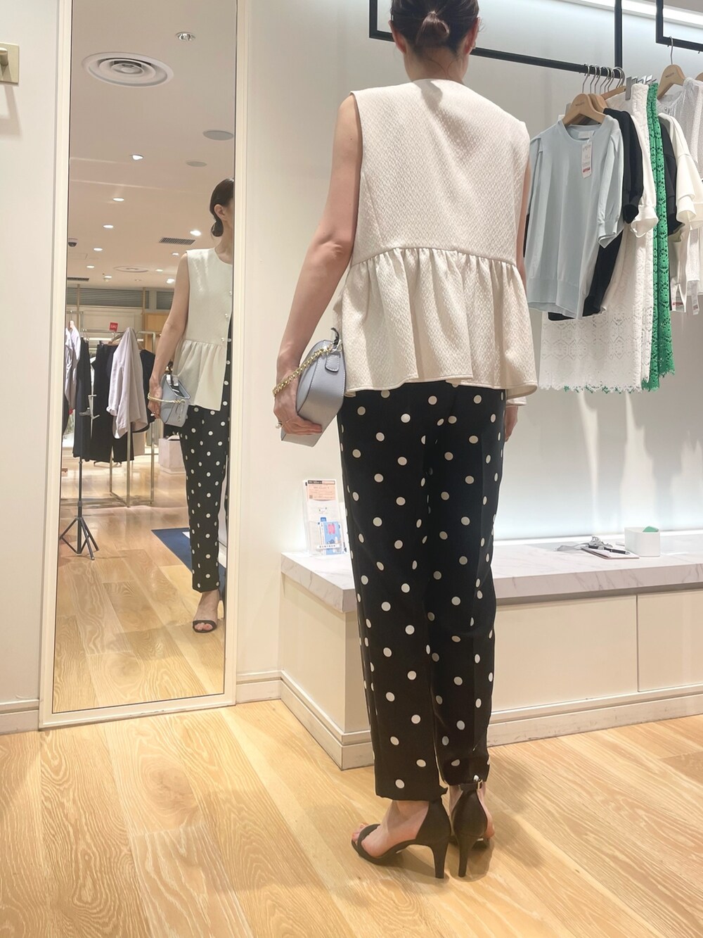 ホワイト系のベスト、ブラック系のその他パンツ、ブルー系のショルダーバッグを着用したレディースの夏コーディネートの5枚目の写真