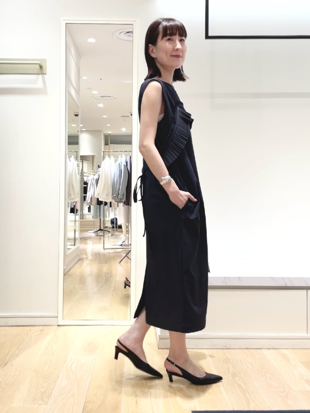 ブラック系のパンプス、ブルー系のワンピース、シルバー系のネックレスを着用したレディースの春コーディネートの3枚目の写真