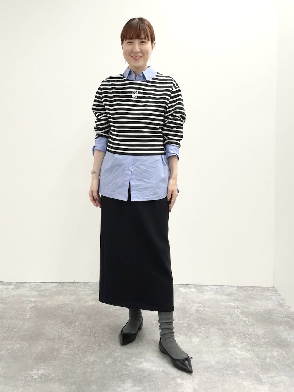 ブラック系のスカート、ブラック系のTシャツ/カットソー、グレー系のピーコートを着用したレディースの秋コーディネートの3枚目の写真