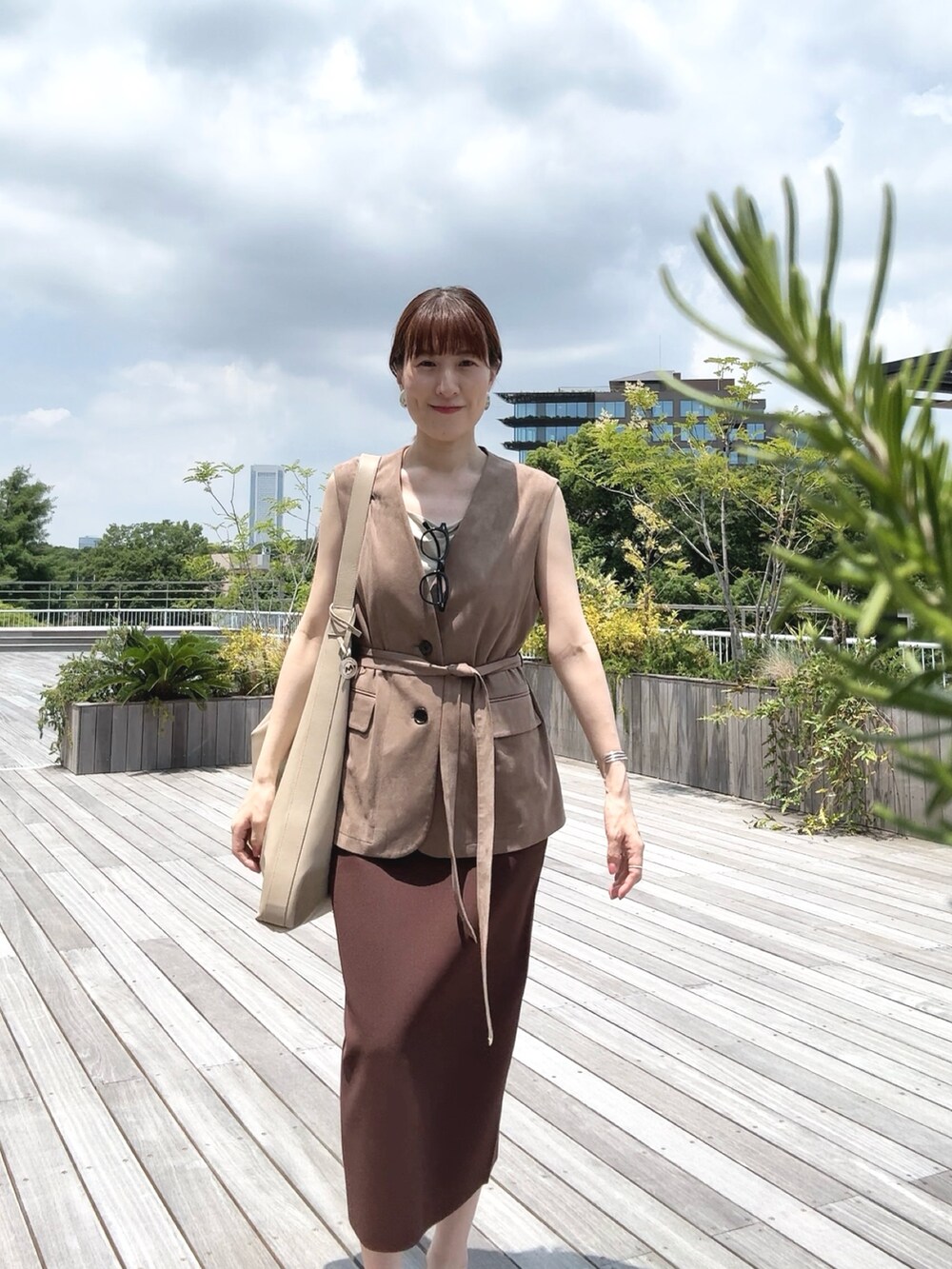 ゴールド系のタンクトップ、ベージュ系のベスト、ベージュ系のショルダーバッグを着用したレディースの秋コーディネートの6枚目の写真