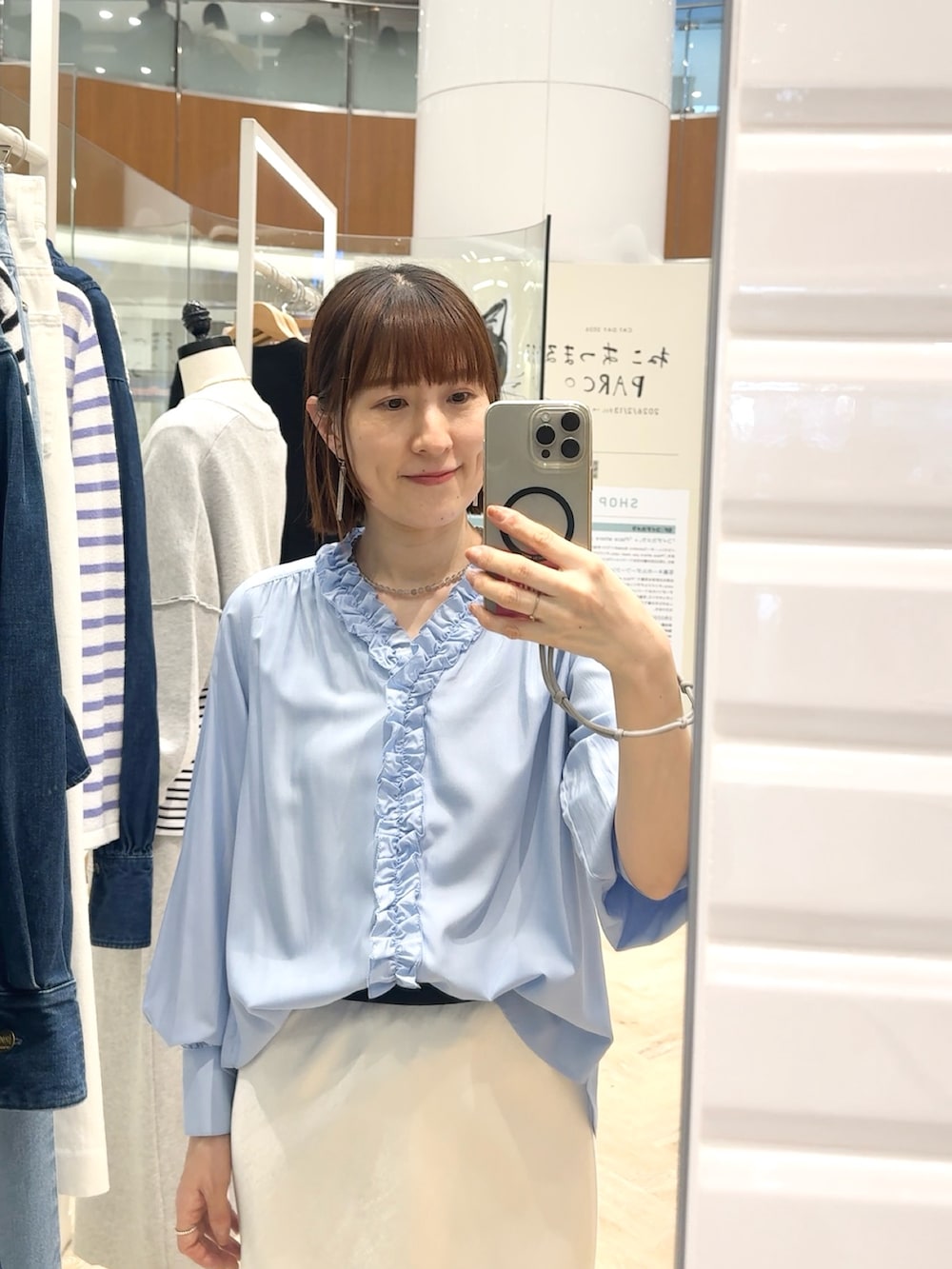 ブルー系のシャツ/ブラウス、ホワイト系のスカート、グレー系のネックレスを着用したレディースの春コーディネートの2枚目の写真