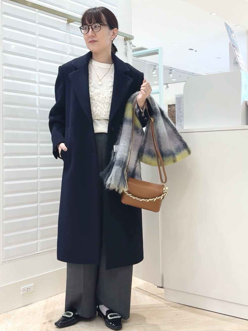 グレー系のその他パンツ、ブルー系のチェスターコート、ホワイト系のベストを着用したレディースの秋コーディネートの2枚目の写真