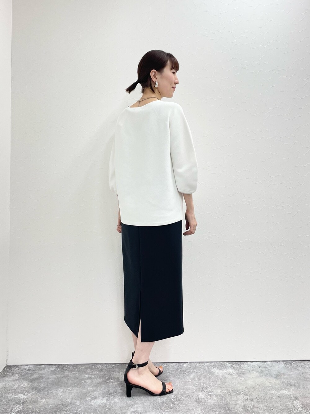 ブラック系のスカート、ホワイト系のニット/セーターを着用したレディースの春コーディネートの3枚目の写真