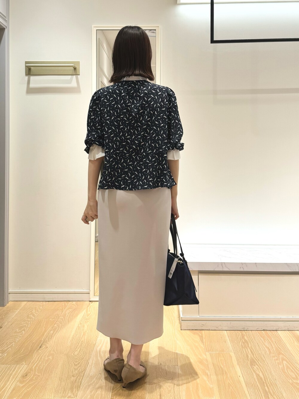 ベージュ系のスカート、ブルー系のトートバッグ、ブルー系のシャツ/ブラウスを着用したレディースの秋コーディネートの5枚目の写真