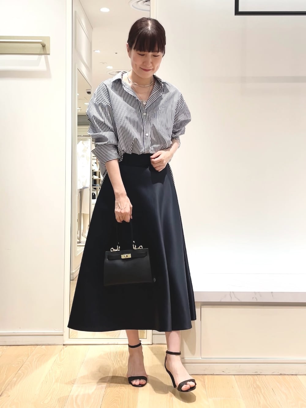 ホワイト系のシャツ/ブラウス、ブルー系のスカート、ブラック系のショルダーバッグを着用したレディースの春コーディネートの4枚目の写真