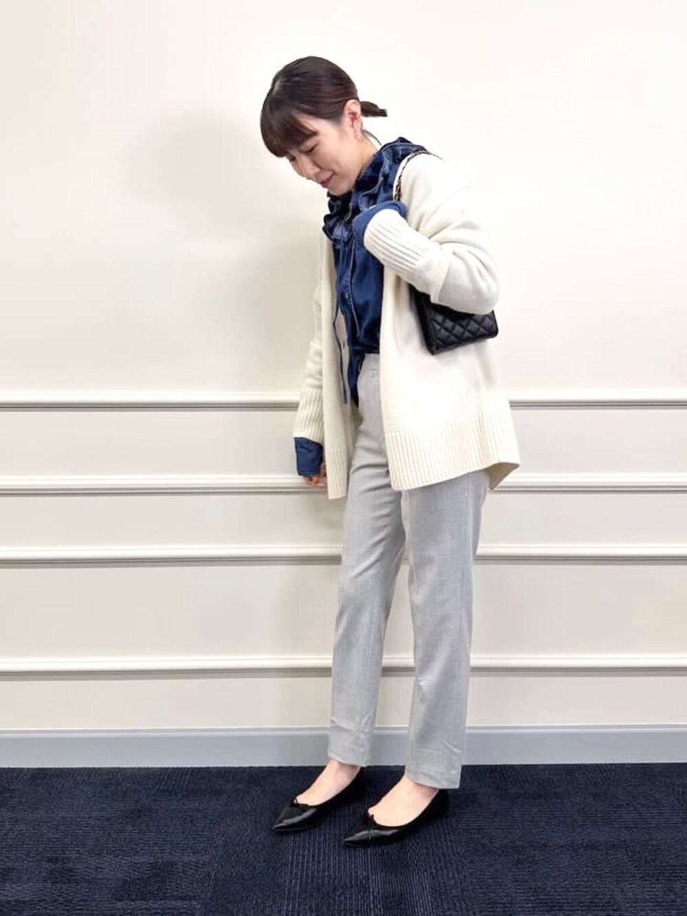 ブラック系のパンプス、グレー系のその他パンツ、ホワイト系のカーディガン/ボレロを着用したレディースの冬コーディネートの5枚目の写真