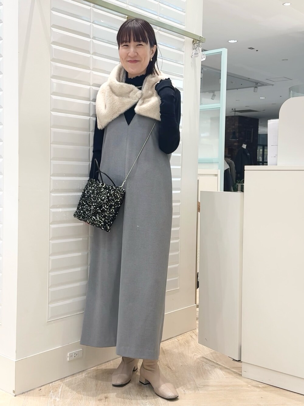 グレー系のワンピース、ブラック系のショルダーバッグ、ブルー系のTシャツ/カットソーを着用したレディースの冬コーディネートの2枚目の写真