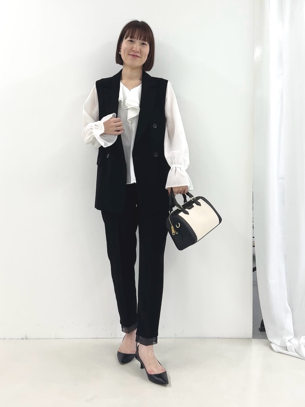 ブラック系のベスト、ホワイト系のシャツ/ブラウス、ブラック系のその他パンツを着用したレディースの冬コーディネートの7枚目の写真