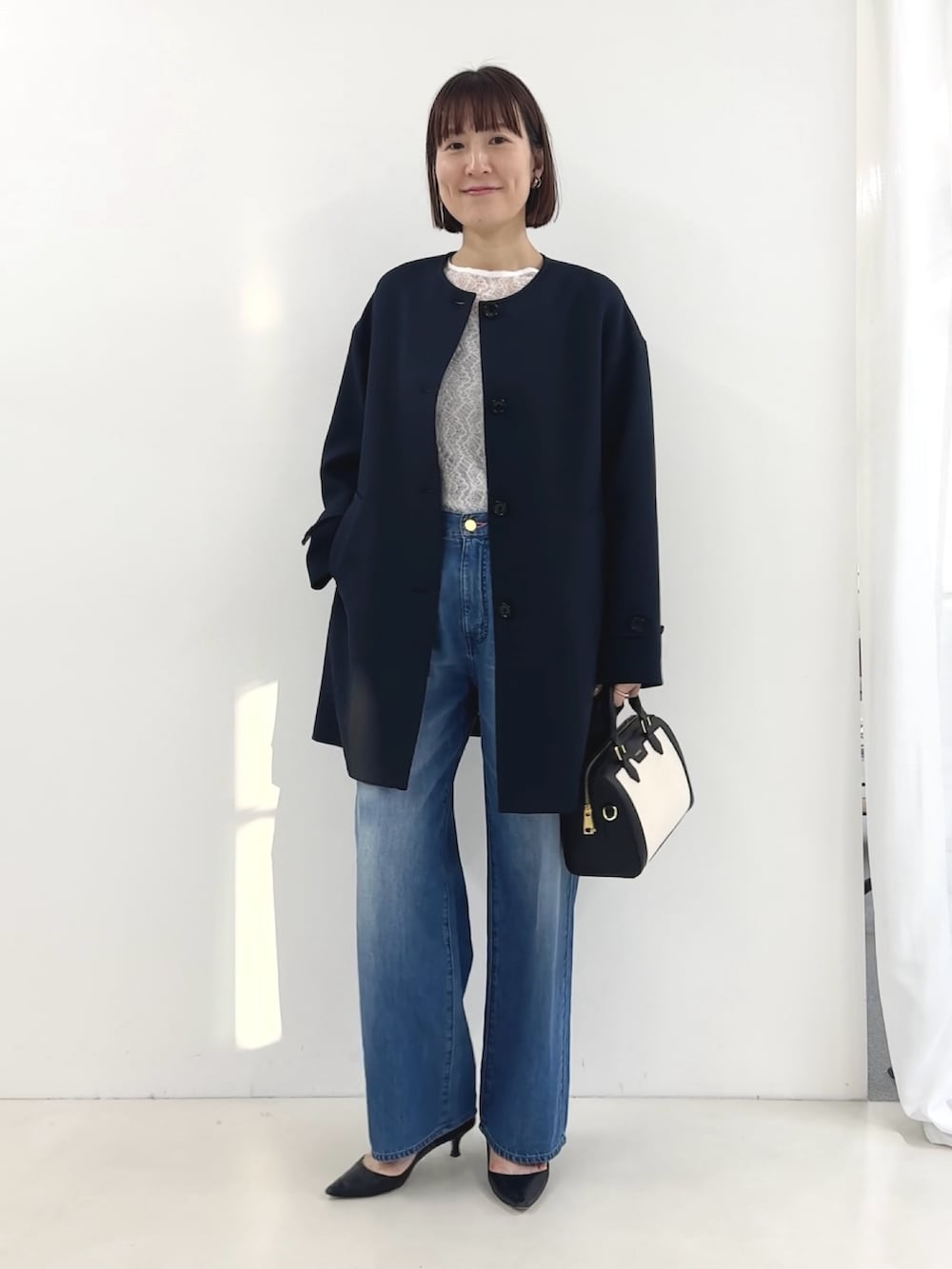 ブラック系のボストンバッグ、ホワイト系のTシャツ/カットソー、ブルー系のステンカラーコートを着用したレディースの冬コーディネートの6枚目の写真