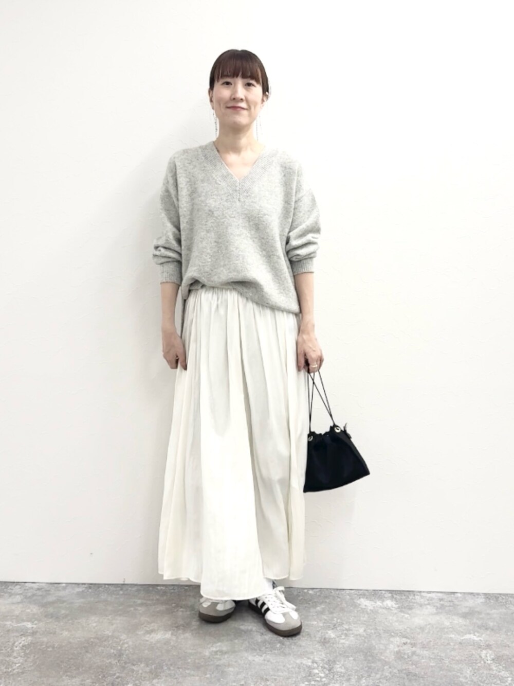 グレー系のニット/セーター、ブルー系のショルダーバッグ、ホワイト系のスカートを着用したレディースの冬コーディネートの5枚目の写真