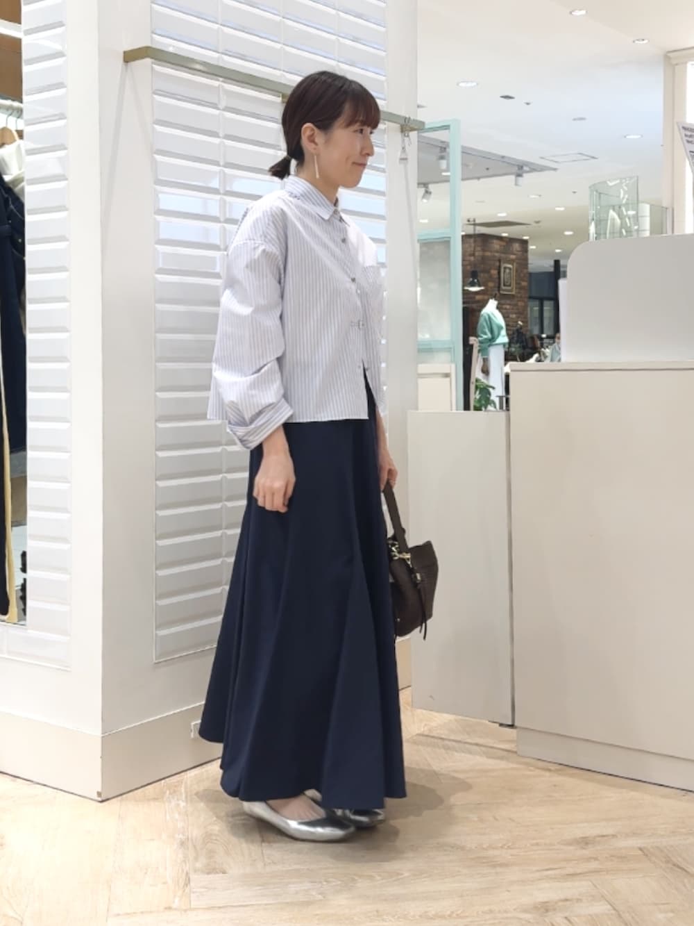 ブルー系のシャツ/ブラウス、ブルー系のスカート、ブラウン系のショルダーバッグを着用したレディースの春コーディネートの5枚目の写真