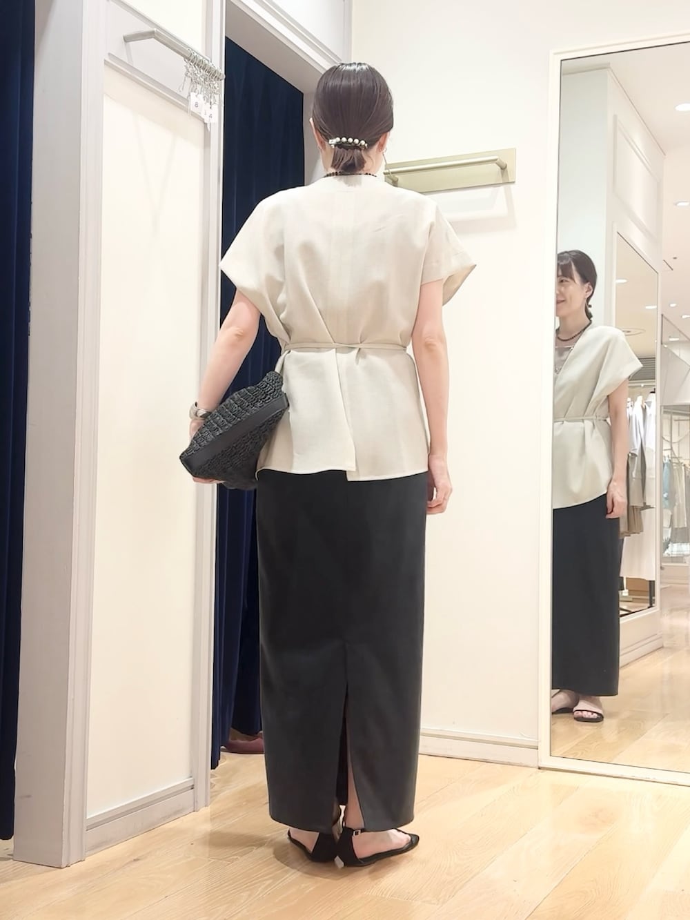 ブラック系のスカート、ブラック系のショルダーバッグ、ベージュ系のタンクトップを着用したレディースの夏コーディネートの3枚目の写真
