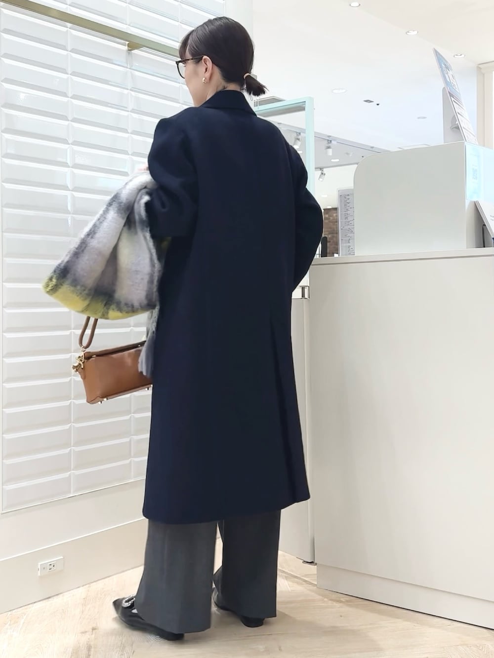 グレー系のその他パンツ、ブルー系のチェスターコート、ホワイト系のベストを着用したレディースの秋コーディネートの3枚目の写真