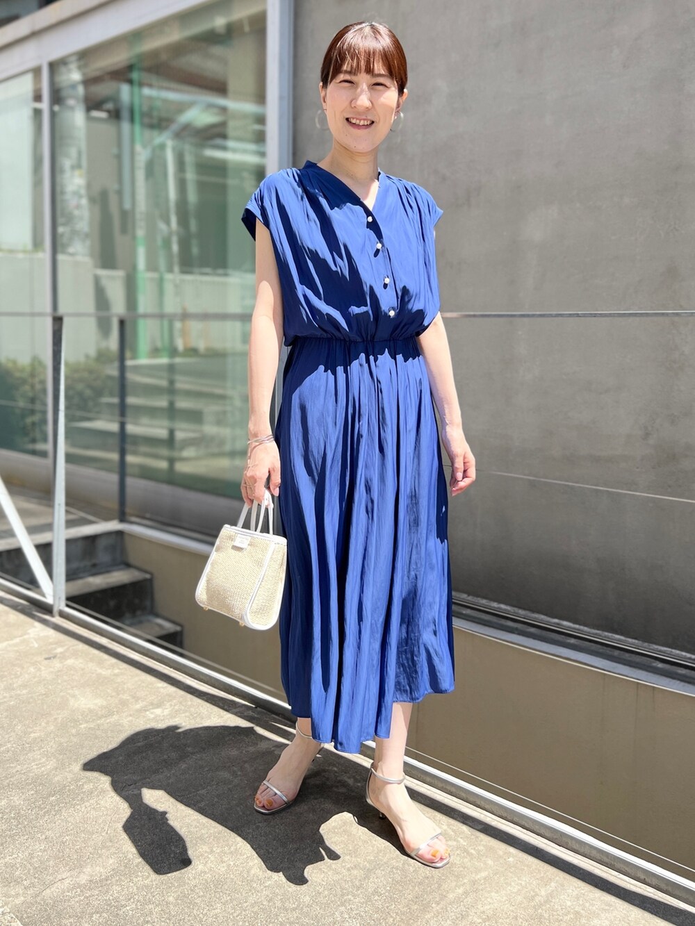 ホワイト系のトートバッグ、ブルー系のワンピース、ホワイト系のサンダルを着用したレディースの春コーディネートの2枚目の写真