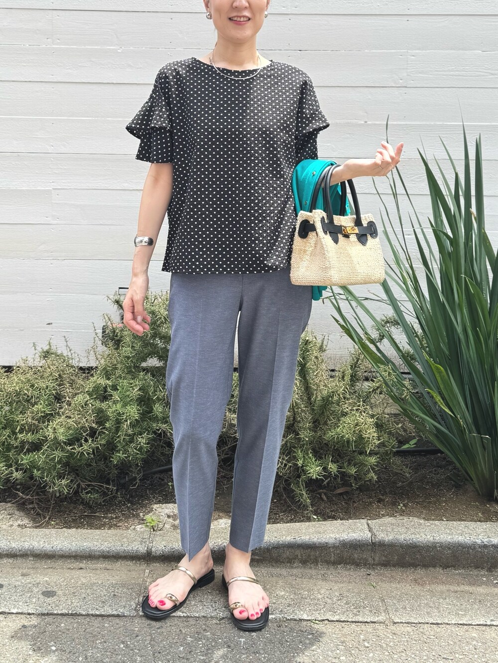 ゴールド系のサンダル、ブルー系のその他パンツ、ブラック系のかごバッグを着用したレディースの春コーディネートの8枚目の写真