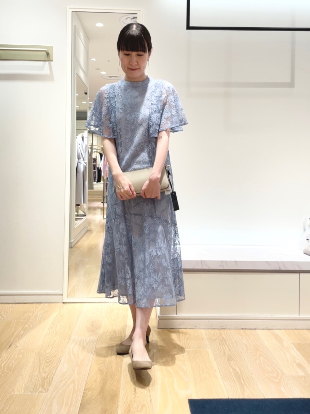 ベージュ系のショルダーバッグ、ブルー系のワンピース、ゴールド系のイヤリングを着用したレディースの秋コーディネートの3枚目の写真